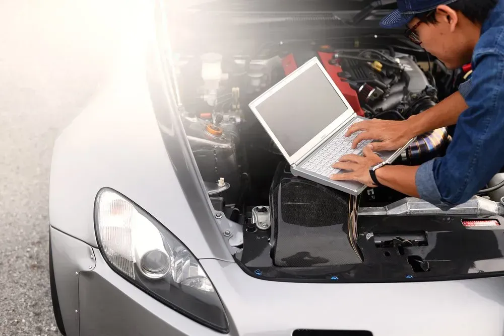 Mechanic Using a Laptop to Diagnose a Car Engine With the Hood Open — Advanced Auto Electrics & Mechanical in Innisfail, QLD