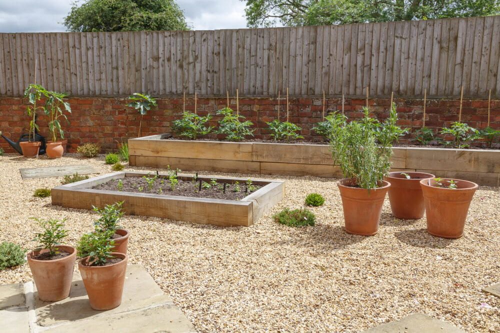 A Garden With Lots Of Potted Plants And A Wooden Fence — Envy Landscape Supplies In Urangan, QLD