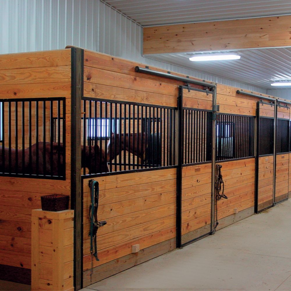 Horse stalls in a barn, wooden construction with metal bars, horses inside.