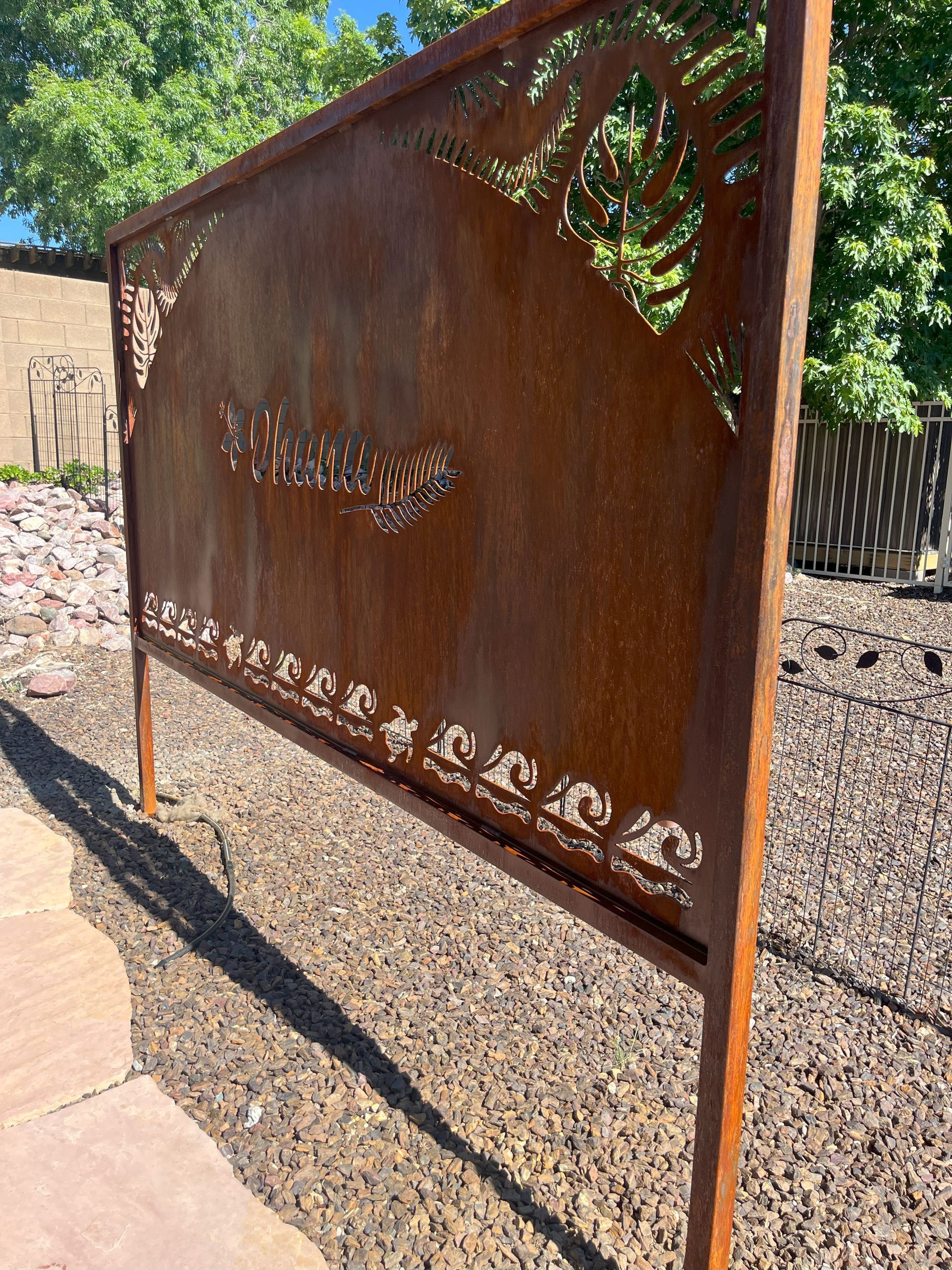 Rusty metal screen with cut-out floral designs, spelling 
