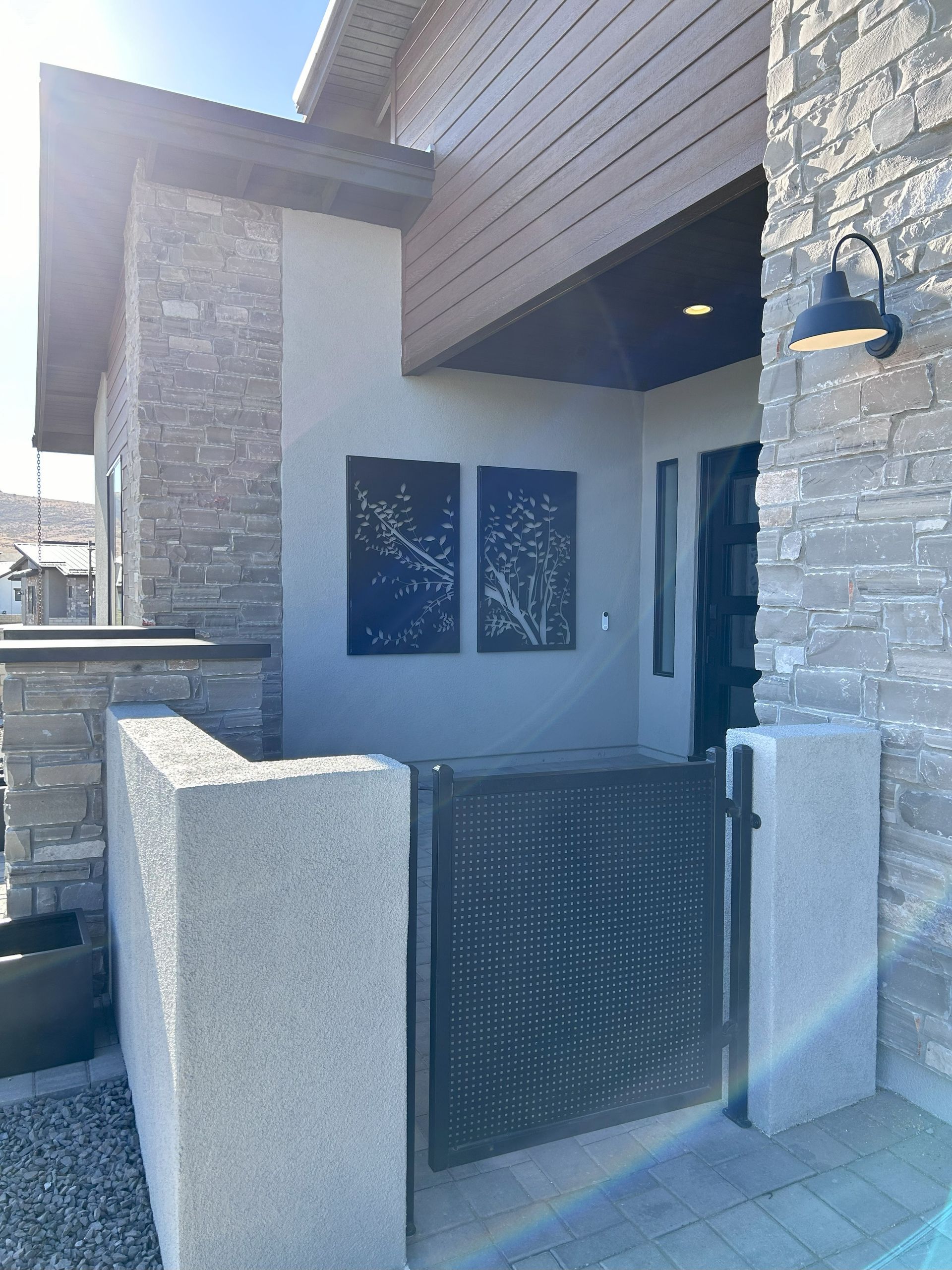Entrance to modern home with stone facade, decorative metal gate, and artwork.