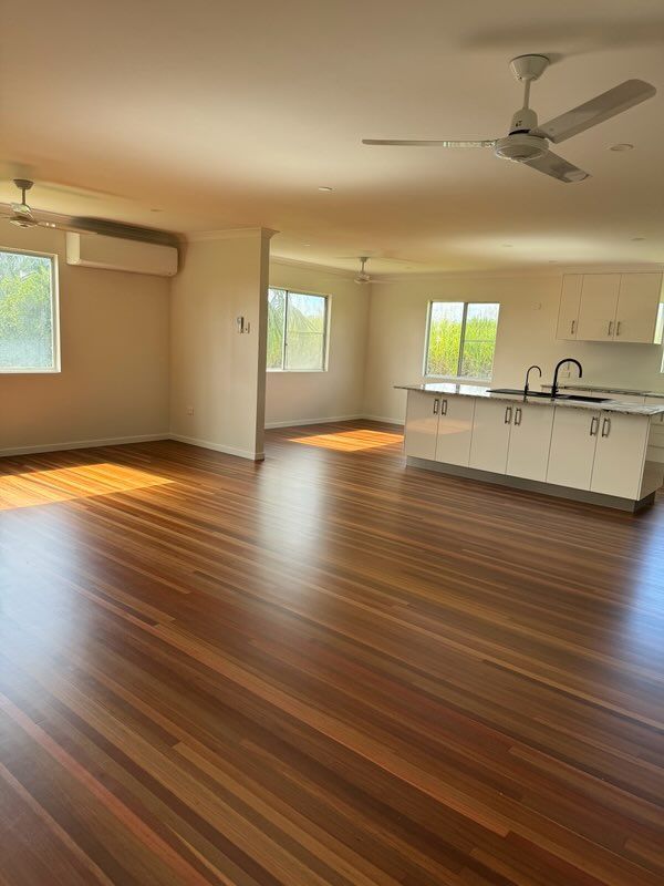 A large empty room with a wooden floor and a ceiling fan — Red Emperor Constructions in Cannonvale, QLD