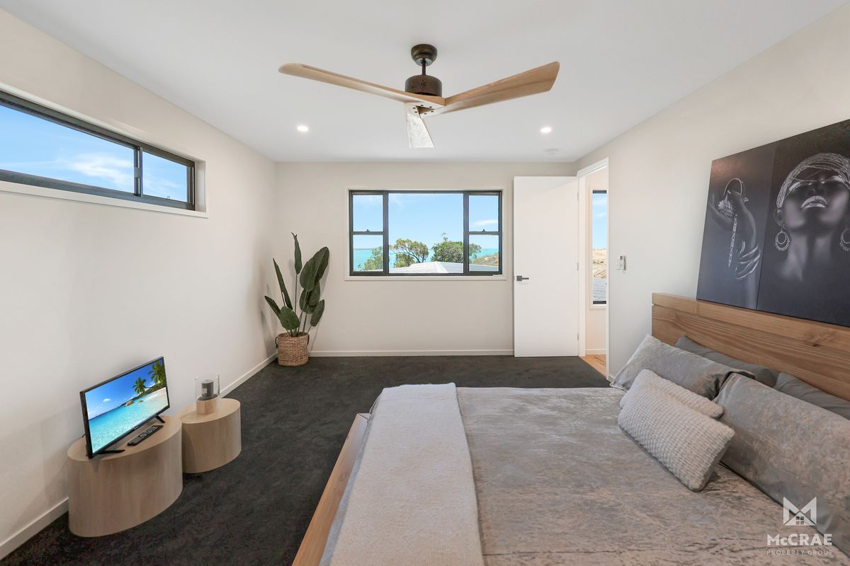 Bedroom With Bed, Art, Tv, and Ceiling Fan, Facing a Window With Ocean View — Red Emperor Constructions in Cannonvale, QLD