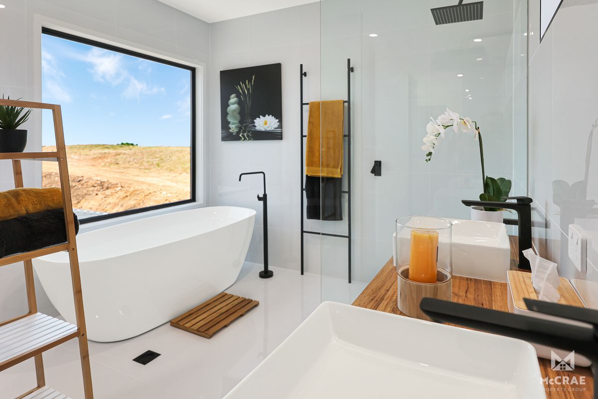 Modern White Bathroom With a Freestanding Tub, Shower, and a Large Window — Red Emperor Constructions in Cannonvale, QLD