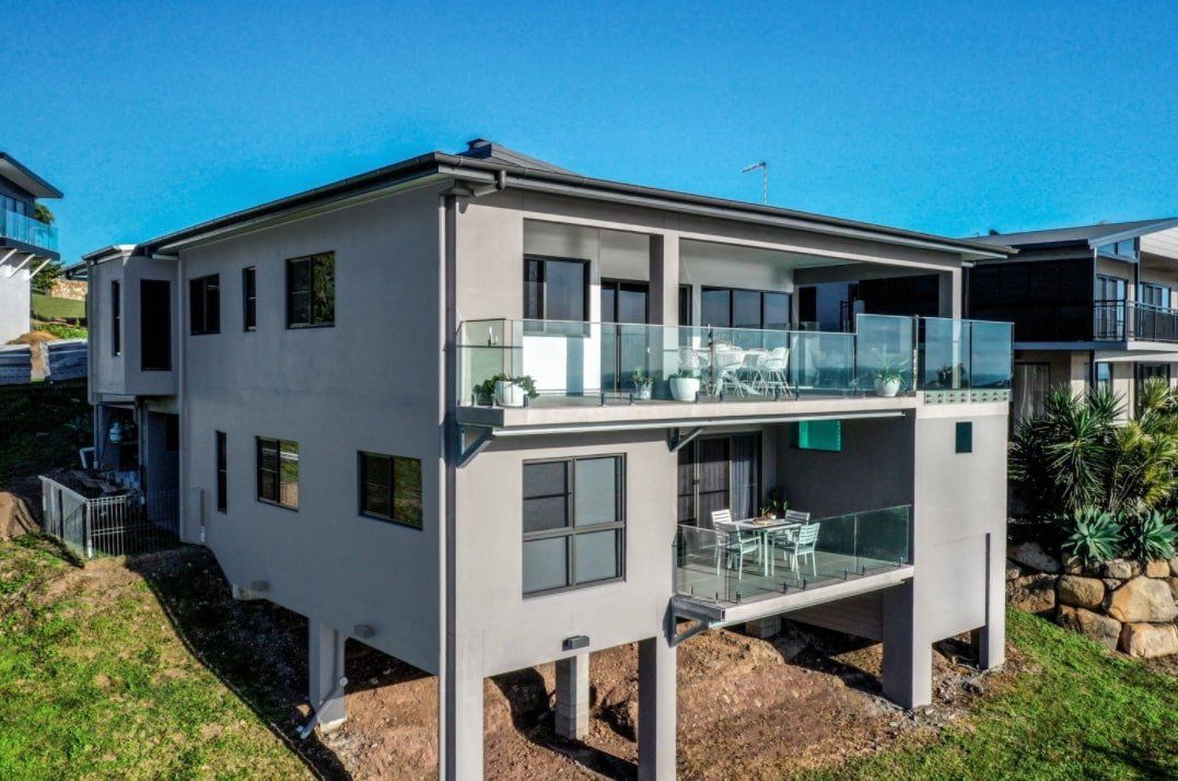 A large house with a lot of windows and balconies is sitting on top of a hill — Red Emperor Constructions in Cannonvale, QLD