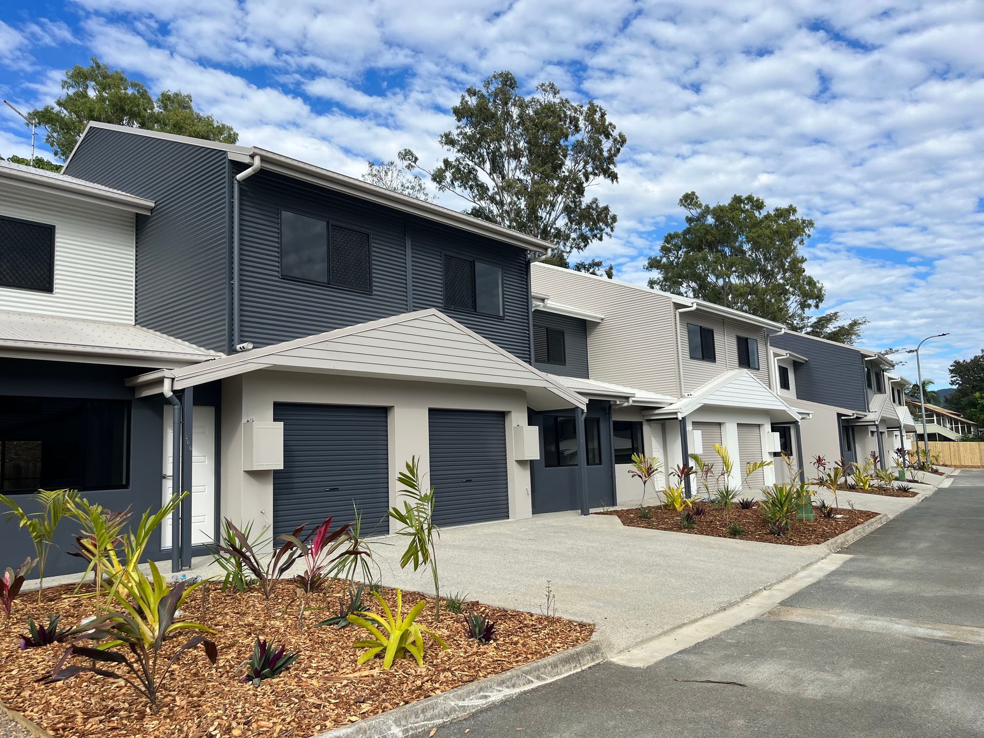 Row of Modern Townhouses With Gray and White Facades, Blue Sky Background — Red Emperor Constructions in Cannonvale, QLD