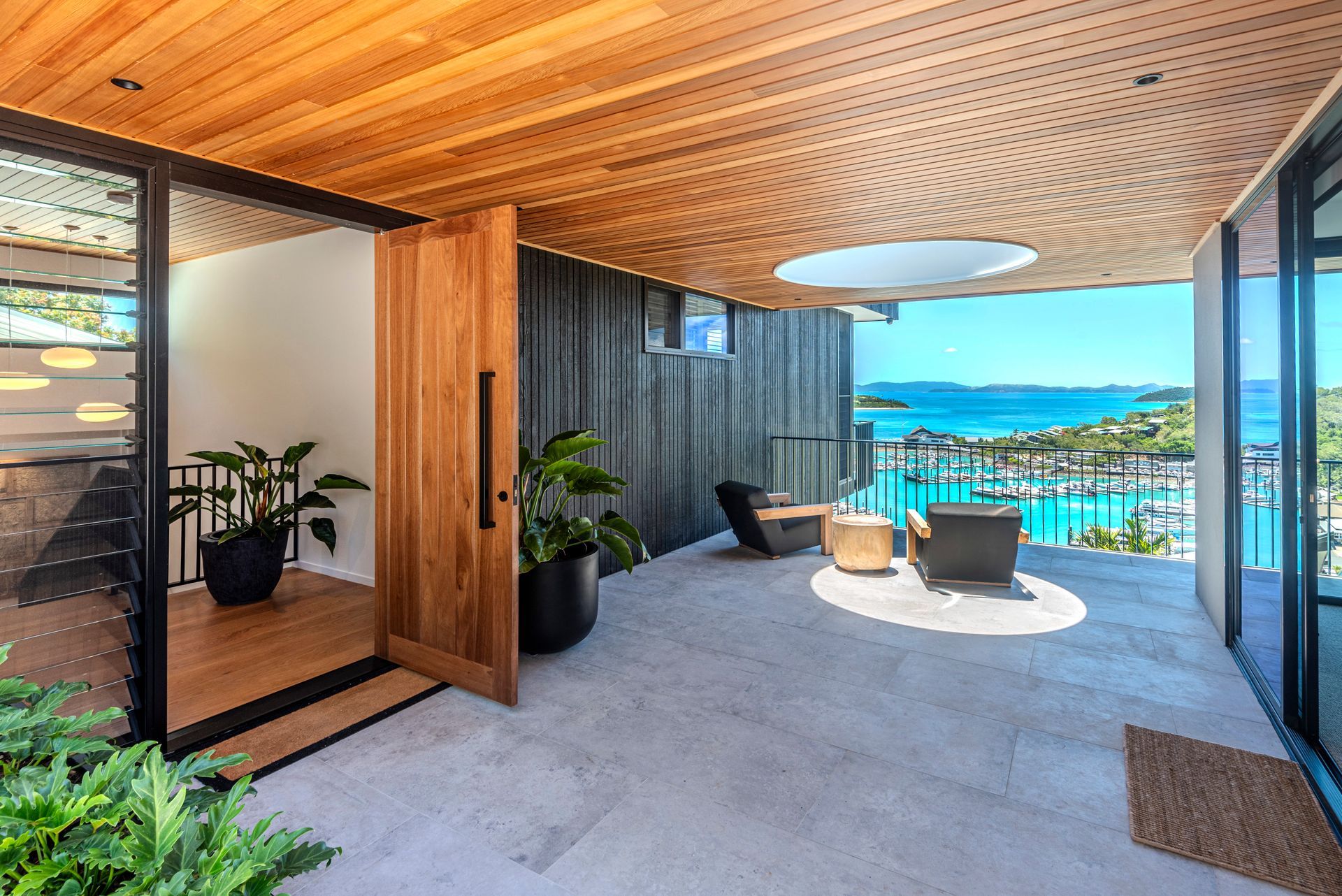 A Bedroom With a Bed, Chairs and Sliding Glass Doors — Red Emperor Constructions in Cannonvale, QLD