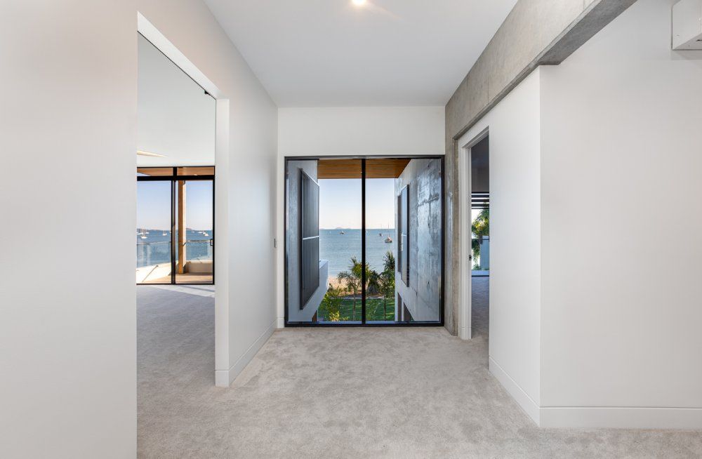 A hallway with sliding glass doors and a view of the ocean — Red Emperor Constructions in Cannonvale, QLD