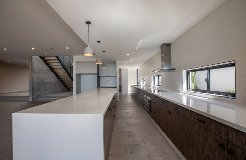 A kitchen with a long island and a staircase in the background — Red Emperor Constructions in Cannonvale, QLD