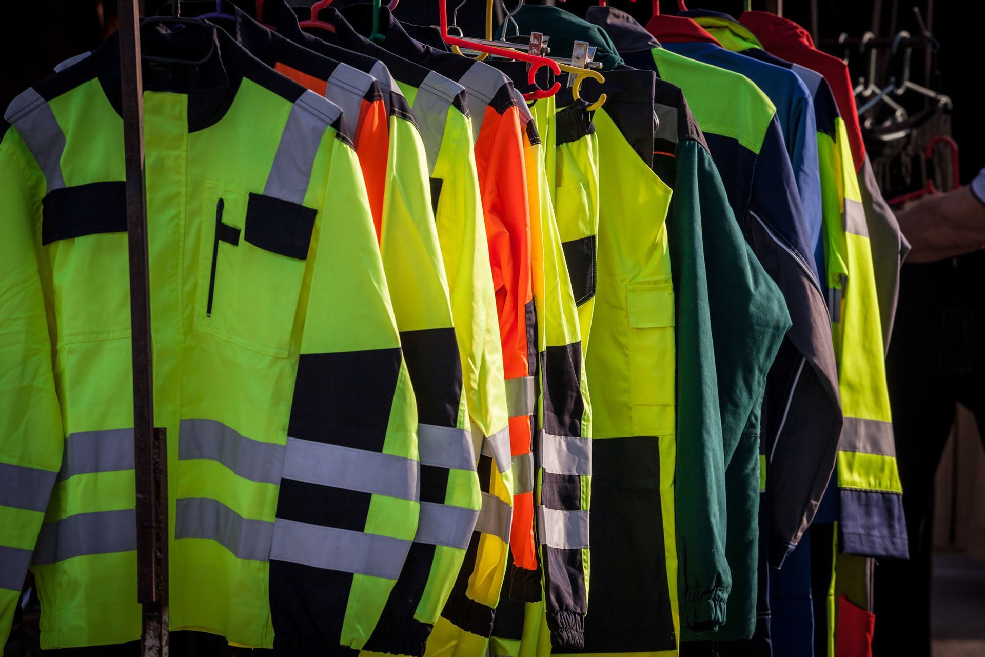 A bunch of safety vests are hanging on a rack.