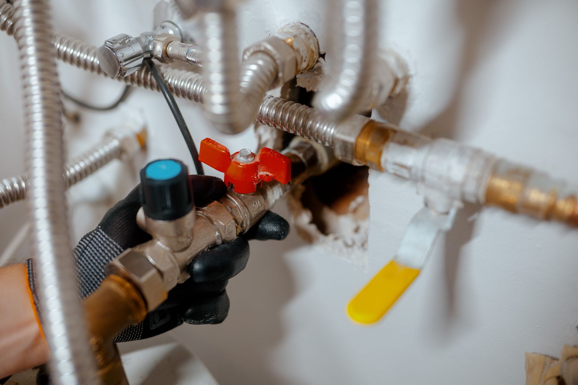 Close-up of metal water pipes and valves with red and yellow handles in a utility area