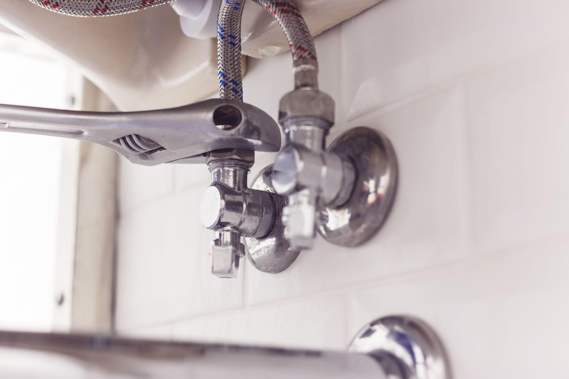 Bathroom sink faucet with a chrome wrench adjusting the valve connection.