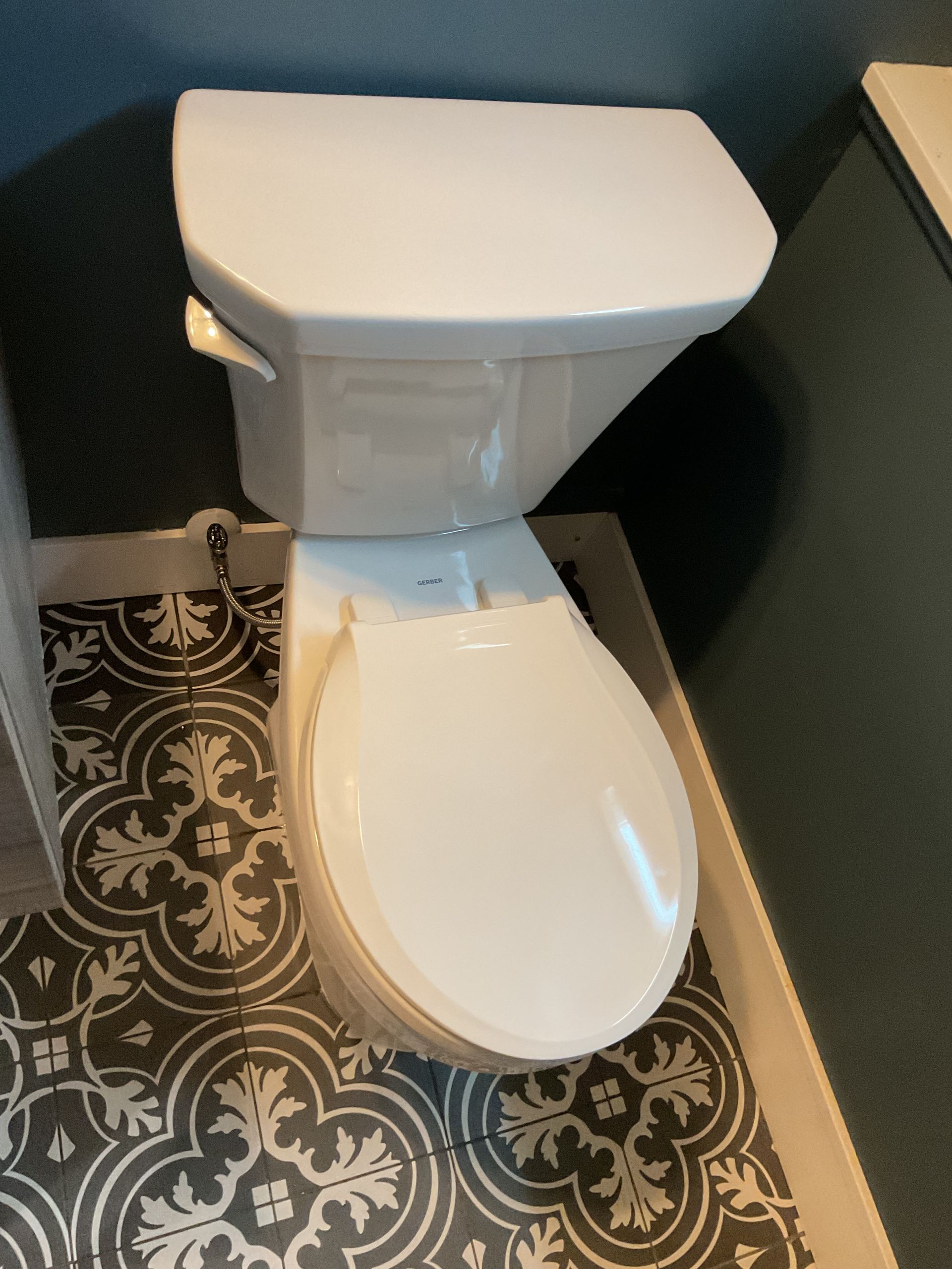 Person replacing a toilet in a white bathroom, with the tank removed and tools nearby