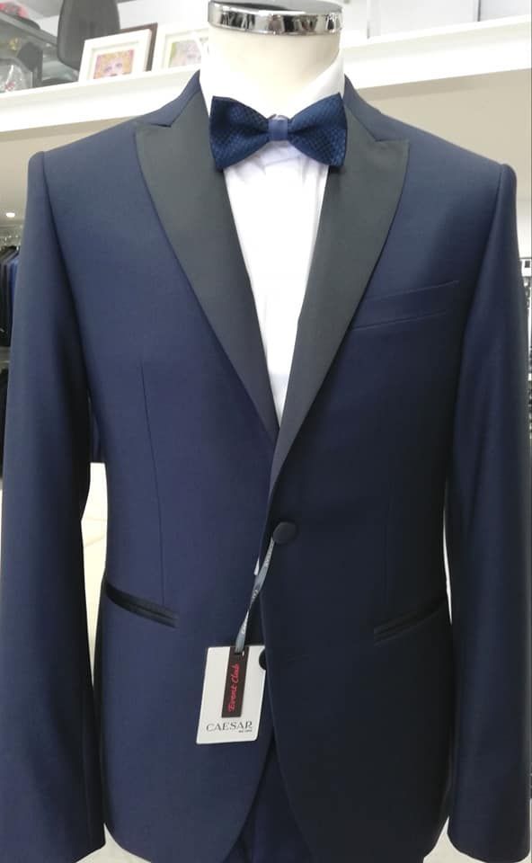 Smoking blu navy con revers in raso, camicia bianca e papillon blu su un manichino