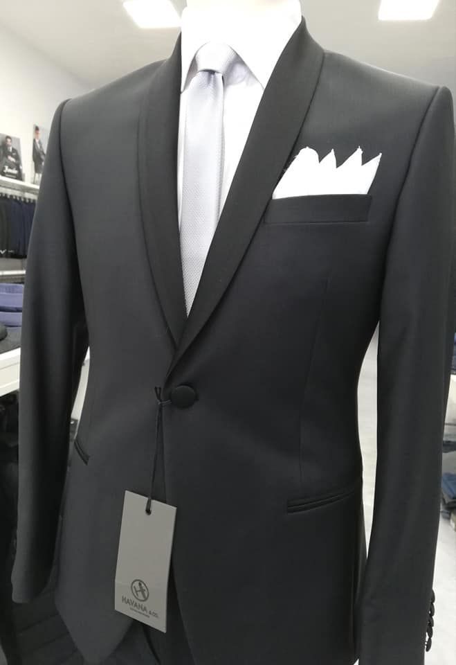 Giacca nera da completo con camicia bianca, cravatta chiara e fazzoletto da taschino bianco su un manichino.