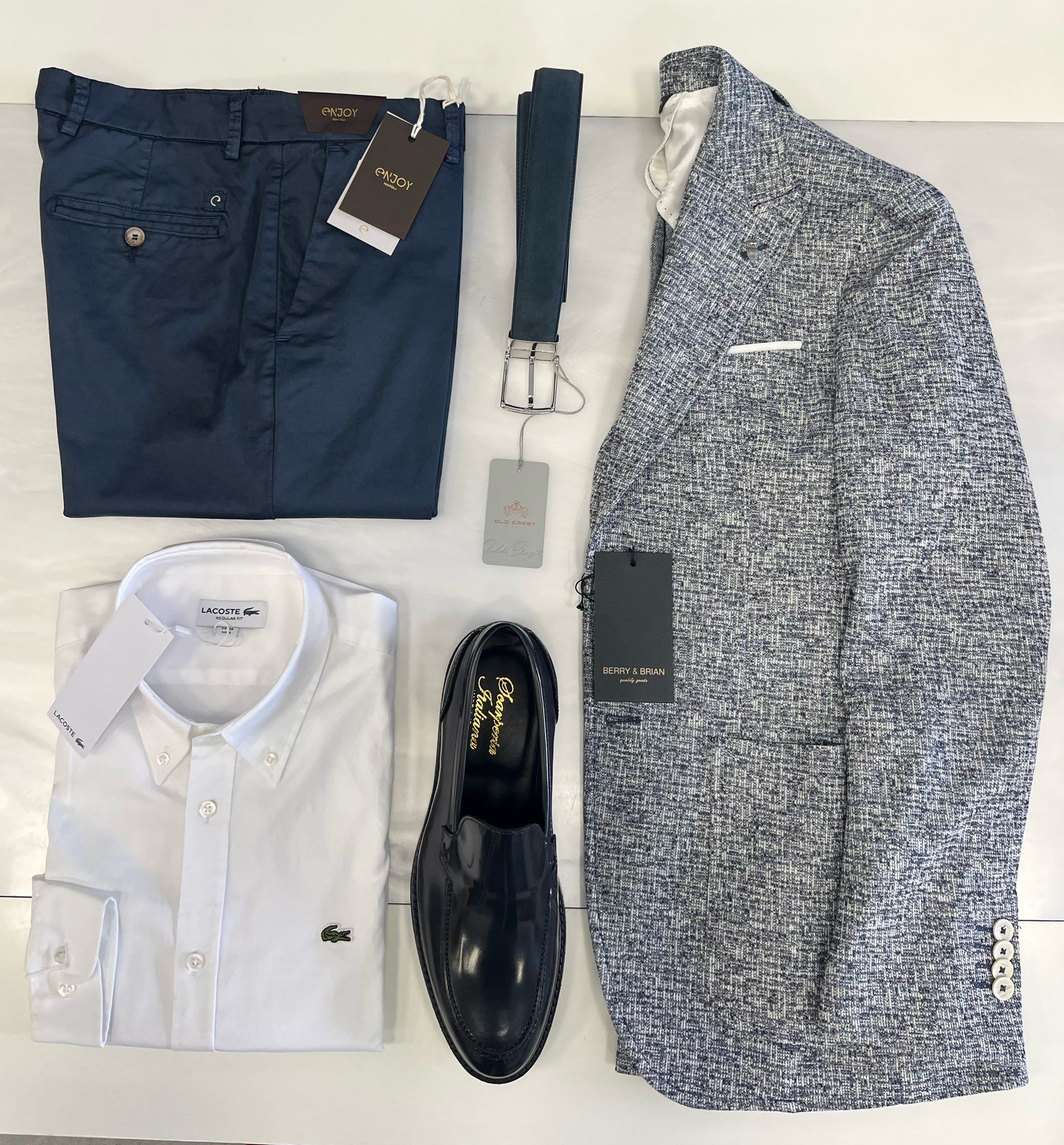 Completo da uomo blu navy, bianco e a fantasia, composto da camicia, pantaloni, cintura, mocassini e giacca.