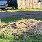 A car is parked in a driveway next to a pile of dirt.