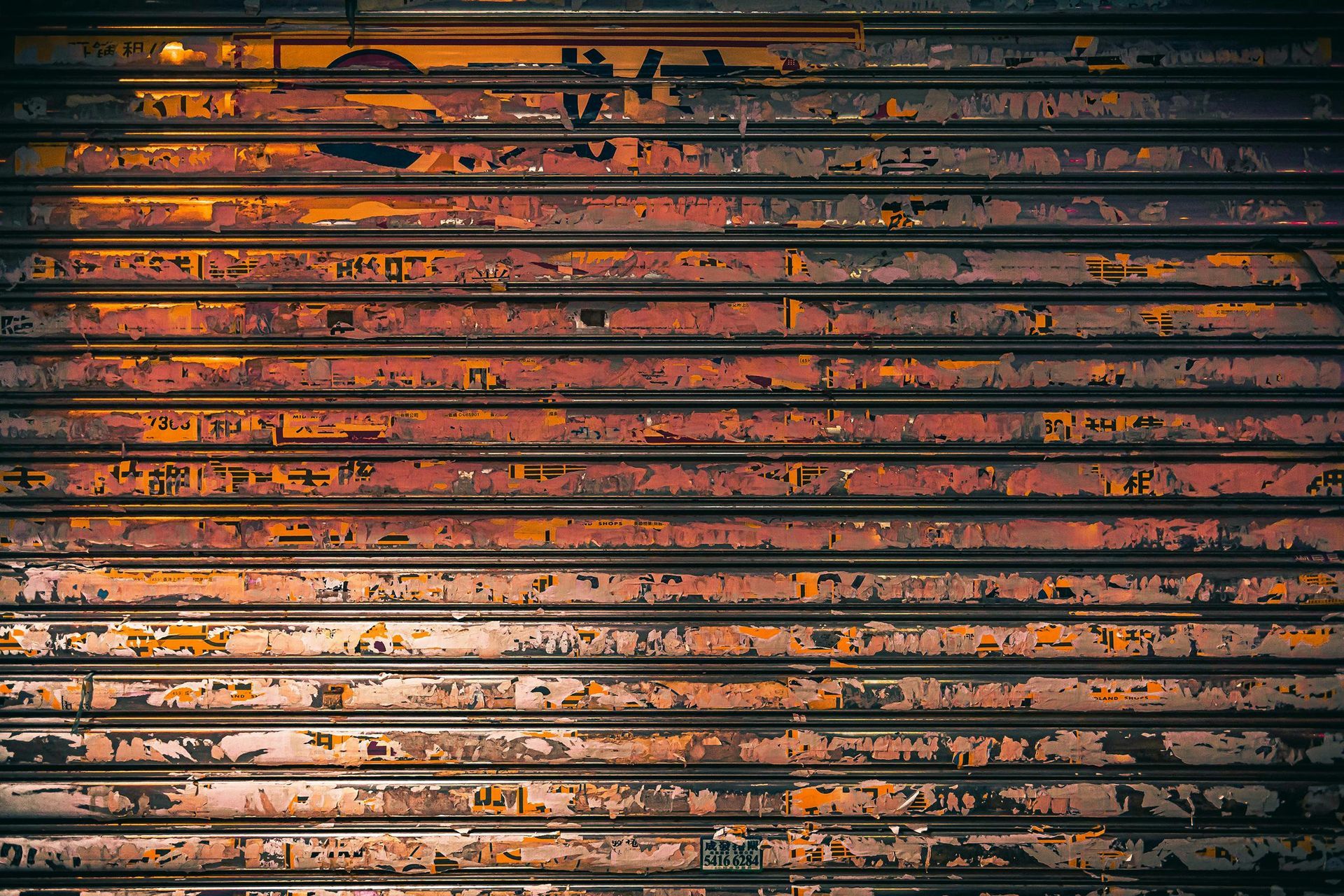 Rusty, orange and brown metal shutter with peeling paint.