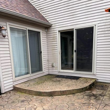 Exterior view of a house with two sliding glass doors and a small patio.