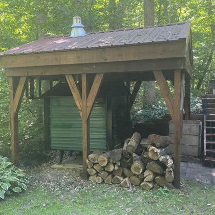 Wooden smoker shed with firewood, forest background.