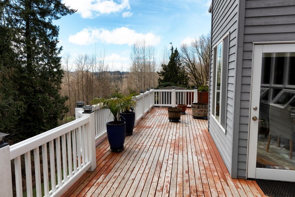 Wooden deck with railings, wet from recent cleaning, surrounded by trees.