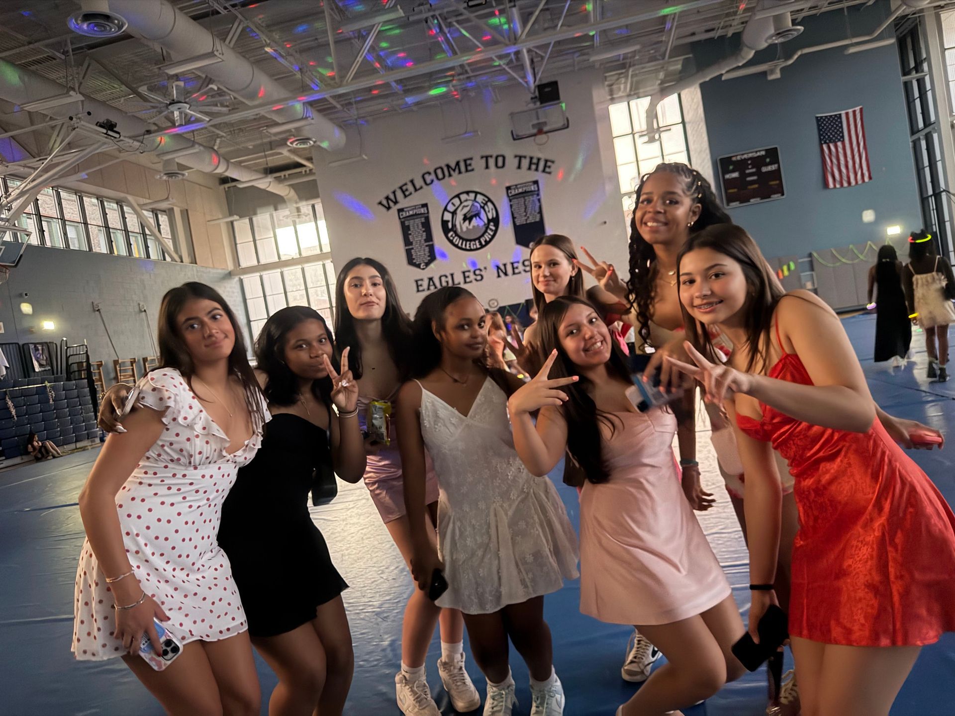 Group posing and smiling in a gym-like hall with neon lights and a