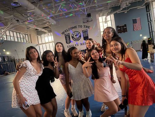 Group posing and smiling in a gym-like hall with neon lights and a
