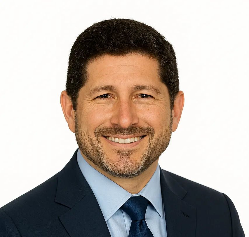 Man in white coat, smiling, in a medical setting.