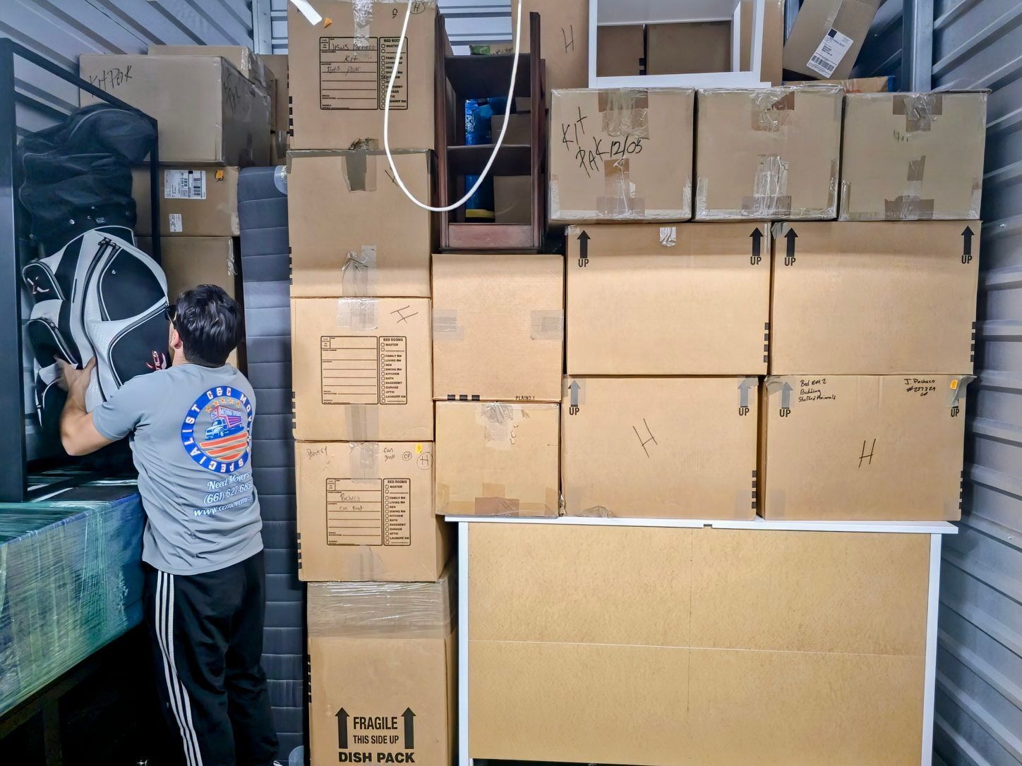 A man is standing in front of a pile of cardboard boxes.