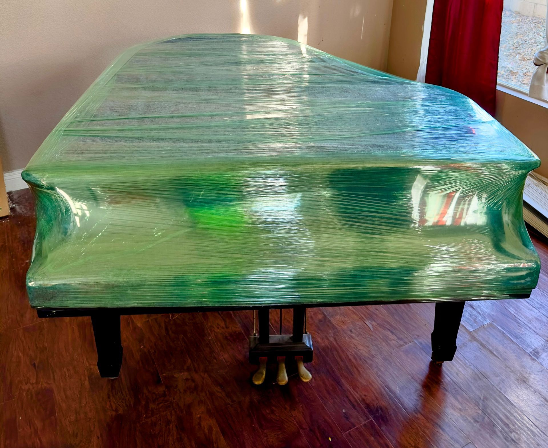 A green piano is sitting on a wooden floor