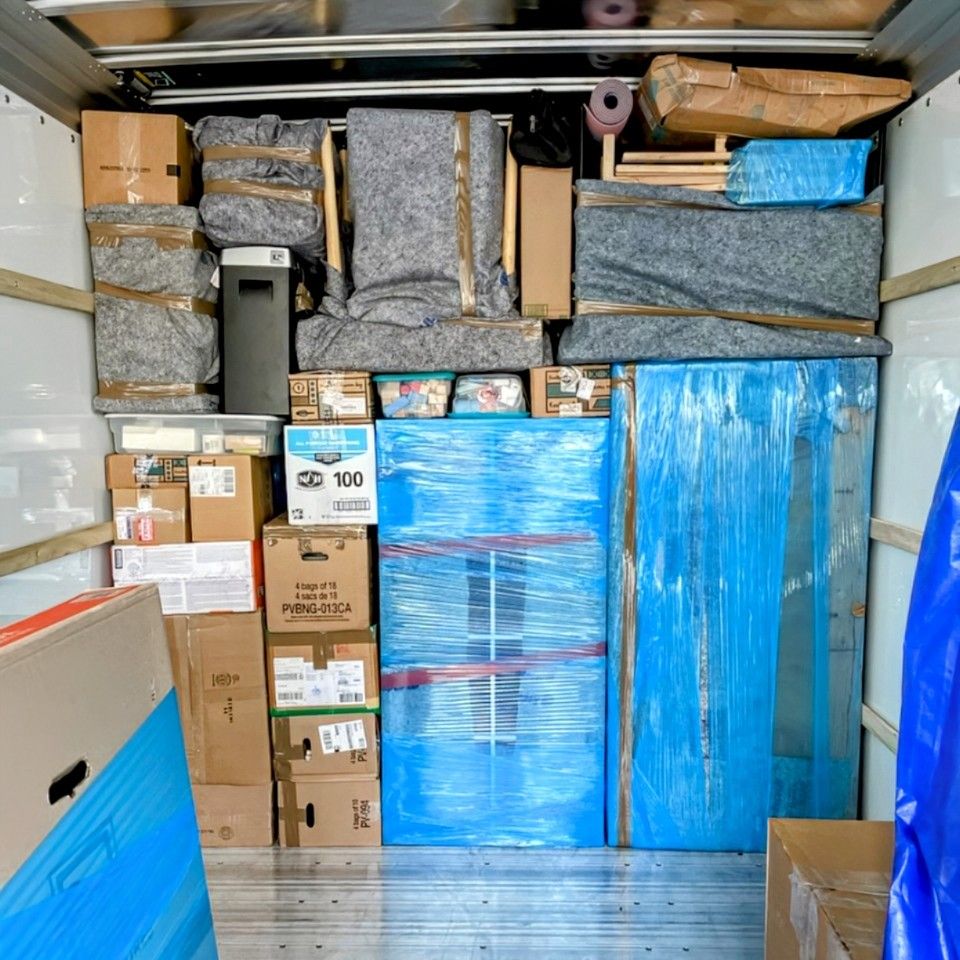 The back of a van filled with appliances wrapped in plastic