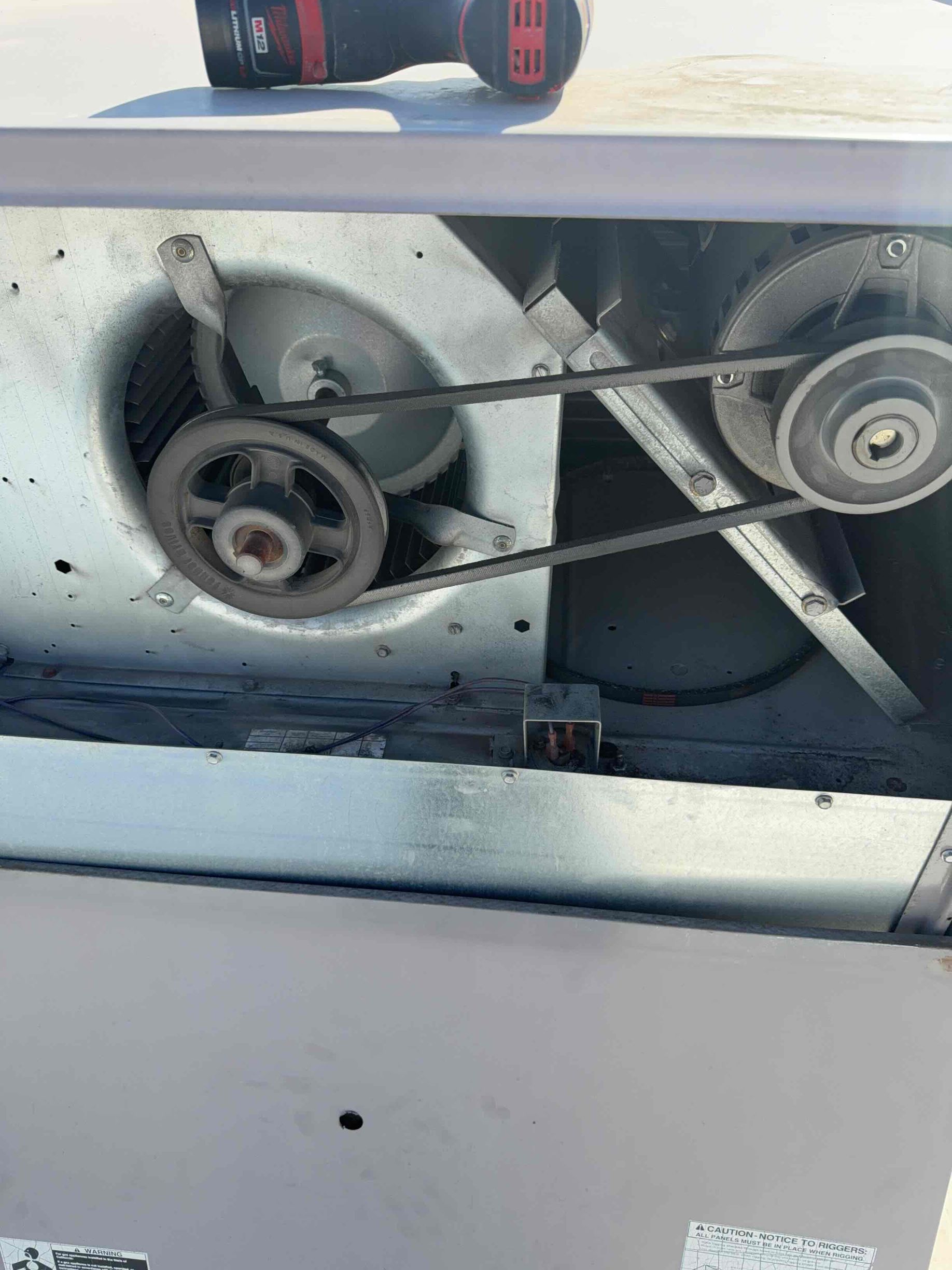 Technician inspecting an outdoor Carrier air conditioner beside a house window