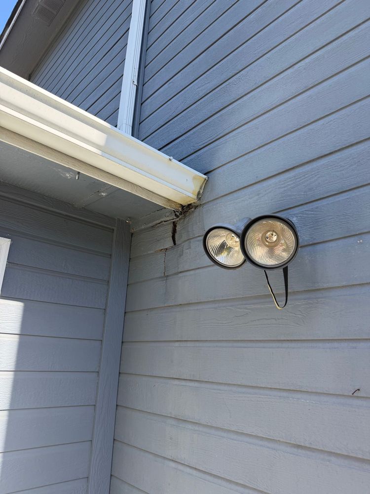 Technician inspecting outdoor HVAC unit beside a house window