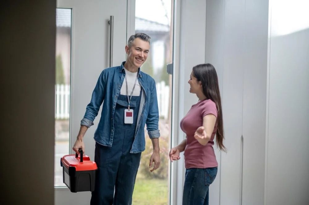 Two people talking in a hallway, one holding a black case with a red lid.