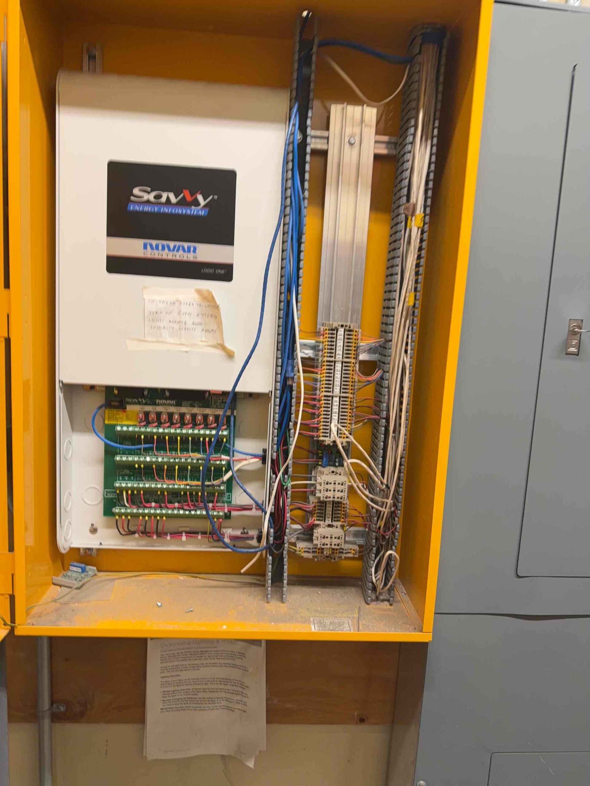 Gloved hands using a digital multimeter to test wiring inside an electrical panel