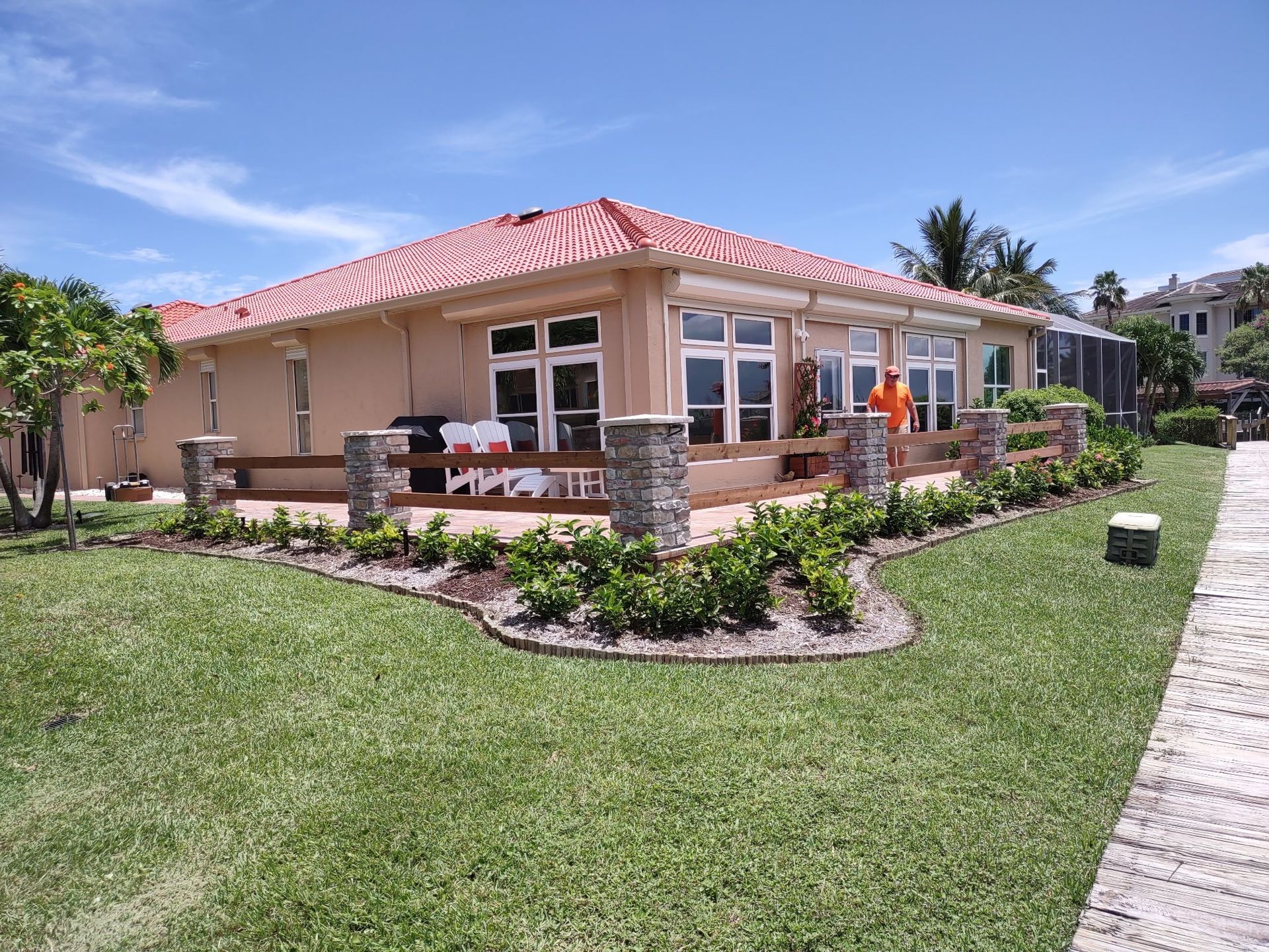 A large house with a red tile roof is surrounded by lush green grass