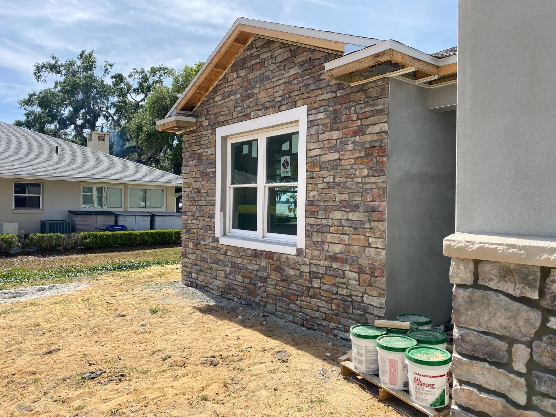 A house with a stone wall and a window is being built.