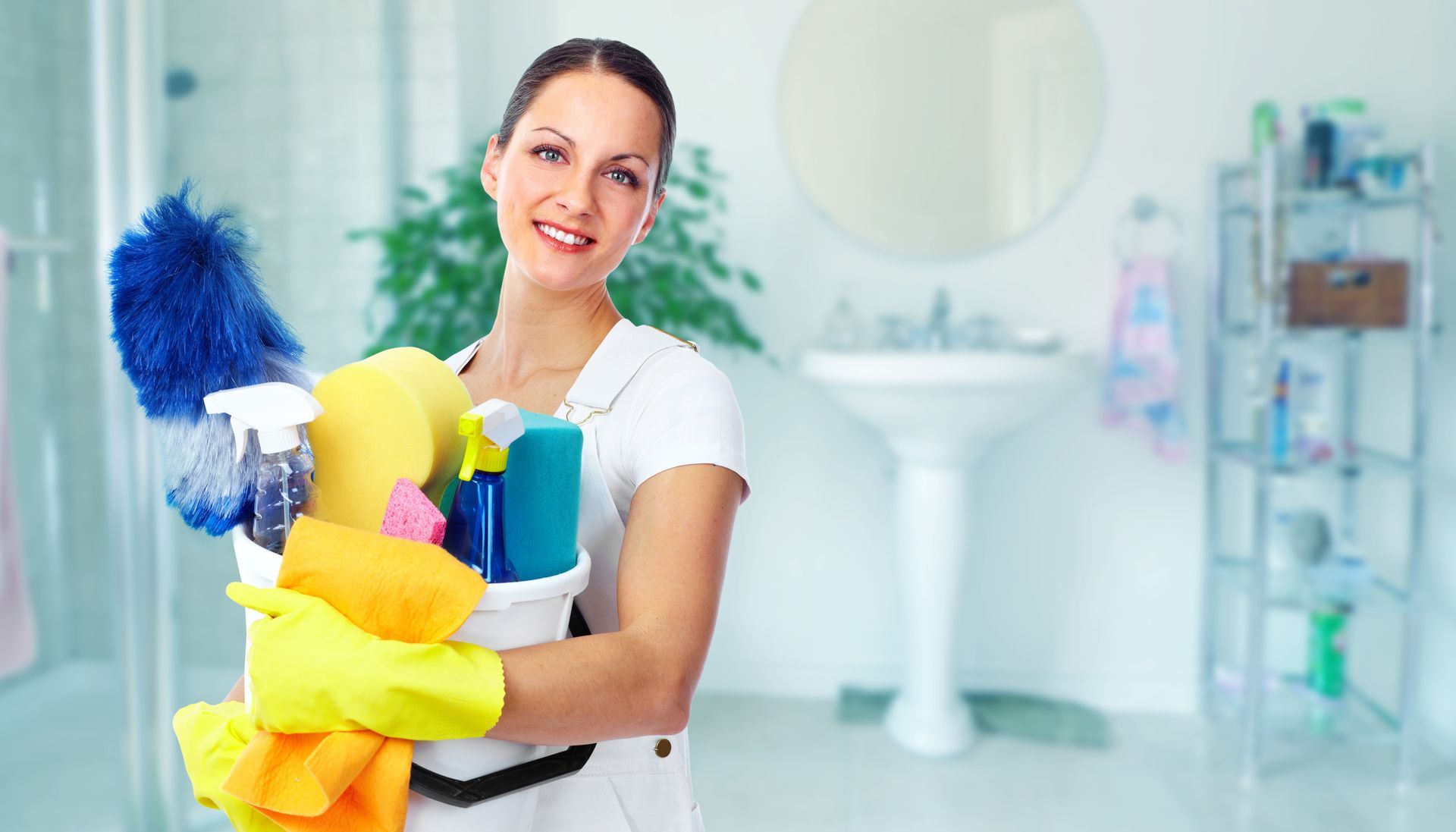 Person holding cleaning supplies and a mop inside a bright room Person holding cleaning supplies and a mop inside a bright room