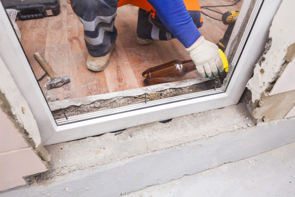 A man is installing a sliding glass door in a house.