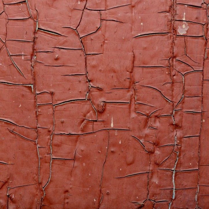 Close-up of cracked red-brown peeling paint on a textured surface in Nashville, TN
