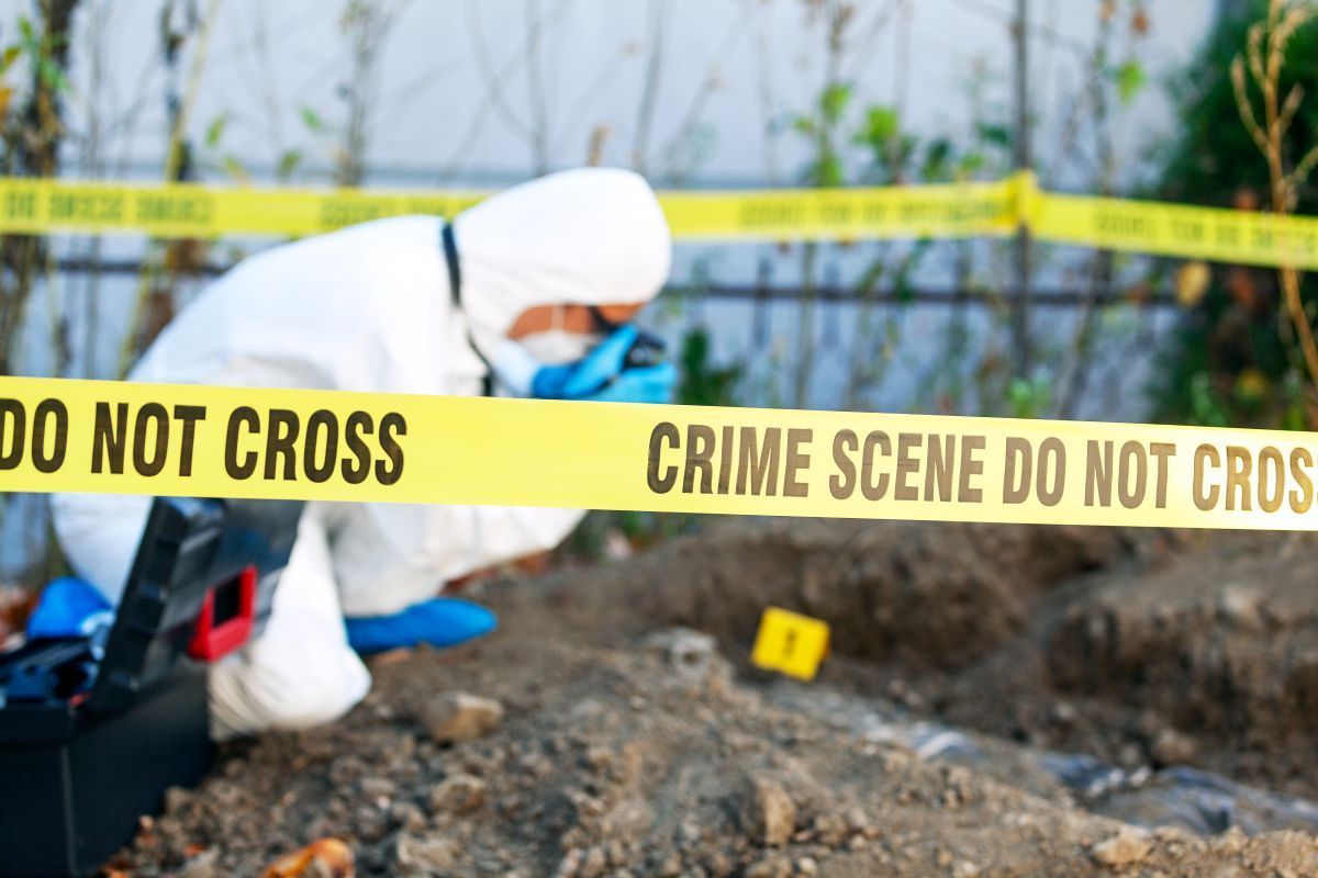 Crime scene with yellow tape and a forensic investigator examining the ground in Nashville, TN