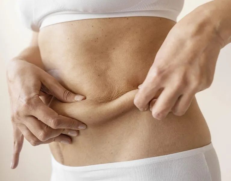 A woman is holding her stomach with her hands.
