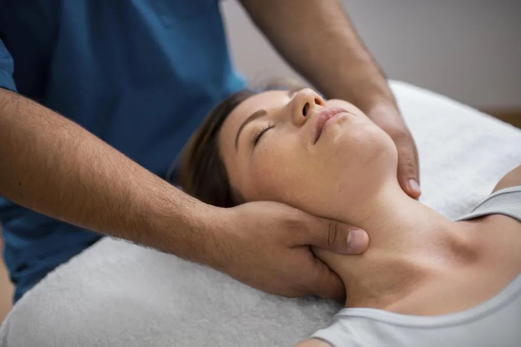 Massage therapist working on a person's neck and shoulders on a treatment table