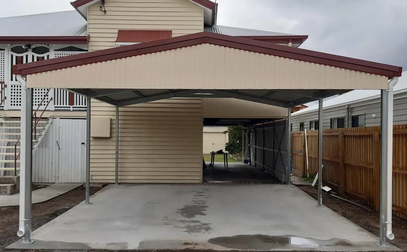 A Newly Constructed Carport with A Gabled Roof Attached to A Light-Colored House — BF Sheds & Garages In Rockhampton, QLD