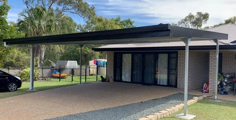 A Modern Metal Carport with A Black Frame Attached to The Front of A Brick House with Large Glass Sliding Doors — BF Sheds & Garages In Rockhampton, QLD