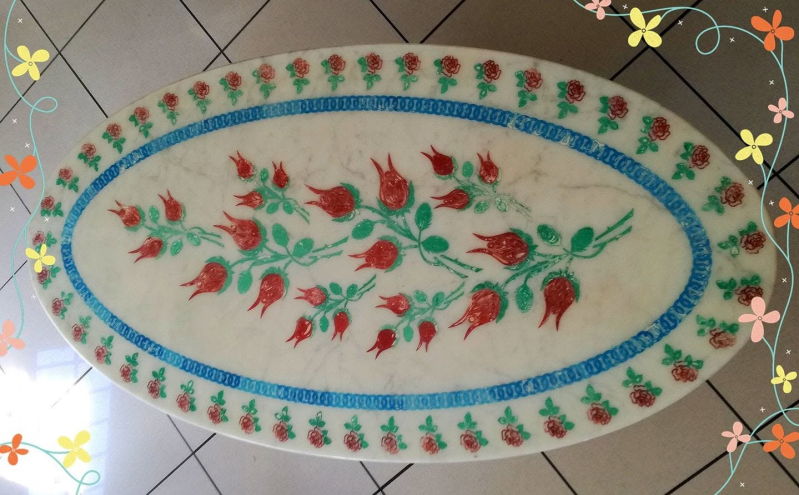 Tappeto ovale con motivo floreale rosso e verde su pavimento piastrellato.