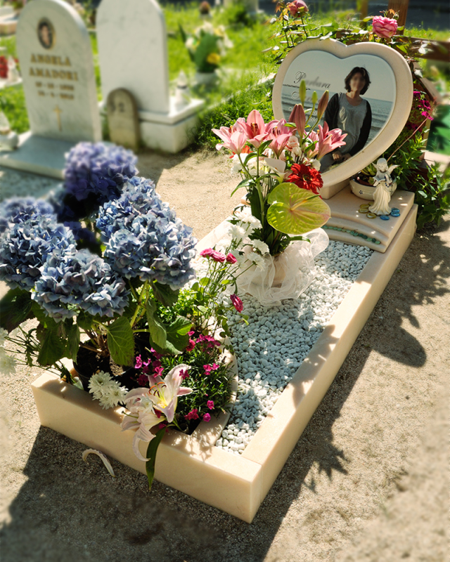 Tombe decorate con fiori, con un ritratto commemorativo a forma di cuore e mazzi di fiori in un cimitero.