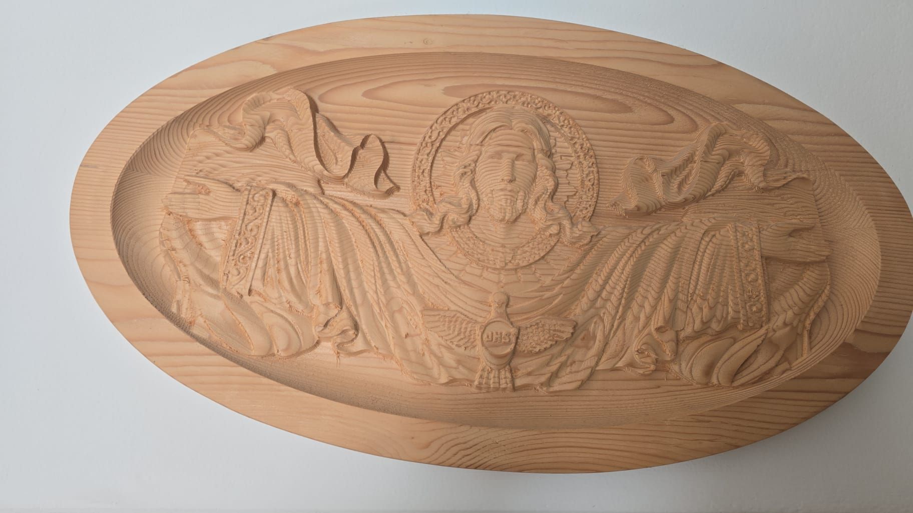 Rilievo ovale in legno raffigurante una figura ammantata con le braccia alzate, in una tonalità di legno naturale.