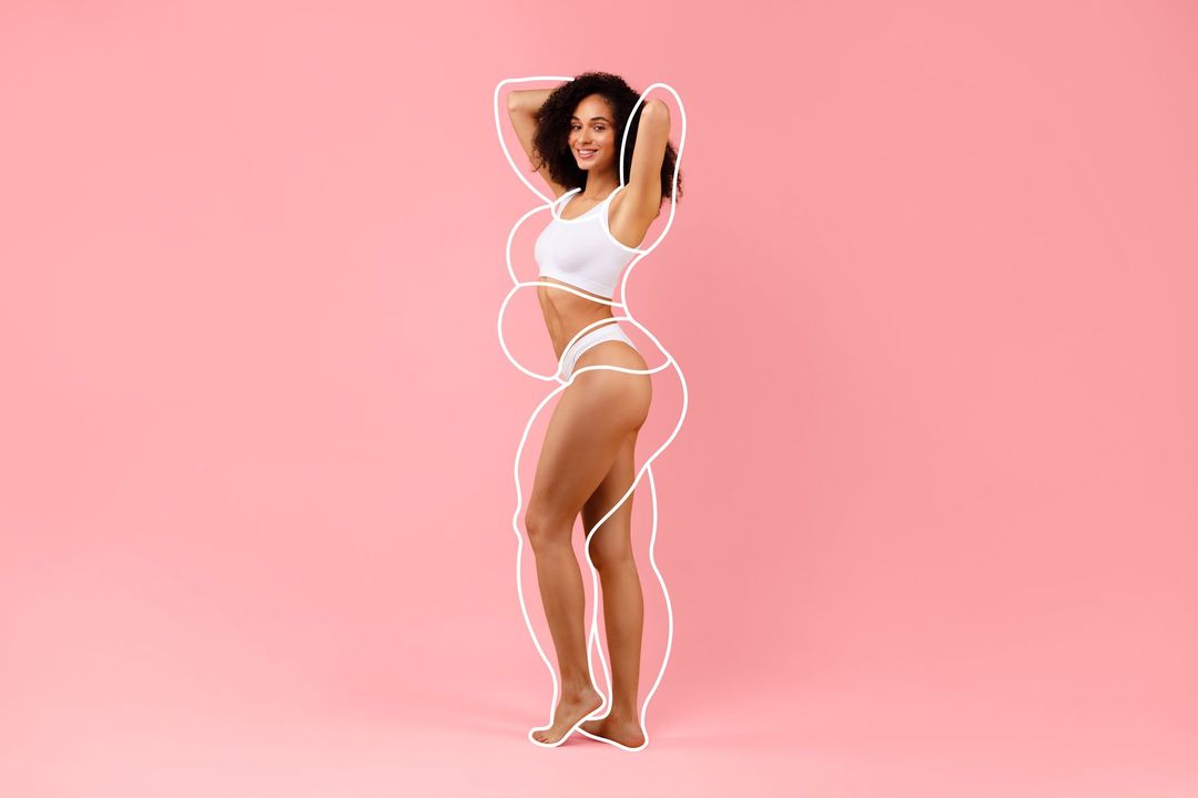 A woman in white underwear is standing on a pink background.