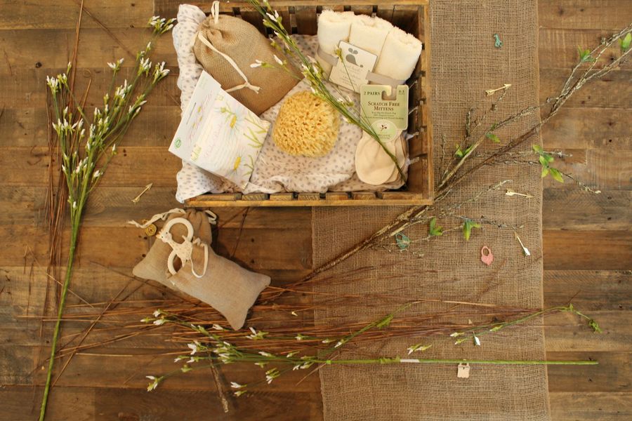 A wooden basket filled with soap and flowers on a wooden table.
